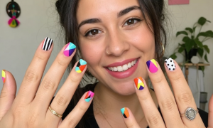 A woman showing off bright colorful nail designs with various geometric patterns