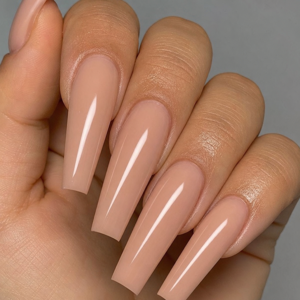 Close up of perfectly shaped long coffin nails with a glossy nude finish