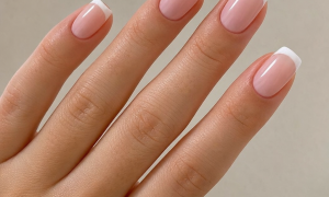 A beautiful classic set of french tip nails on a well-manicured hand in ENGLISH